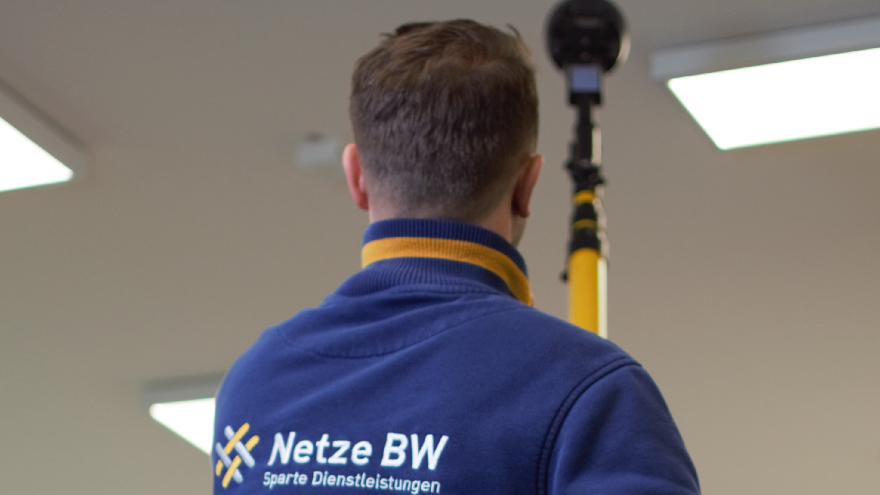 Netze BW Mitarbeiter von hinten mit Messgerät.