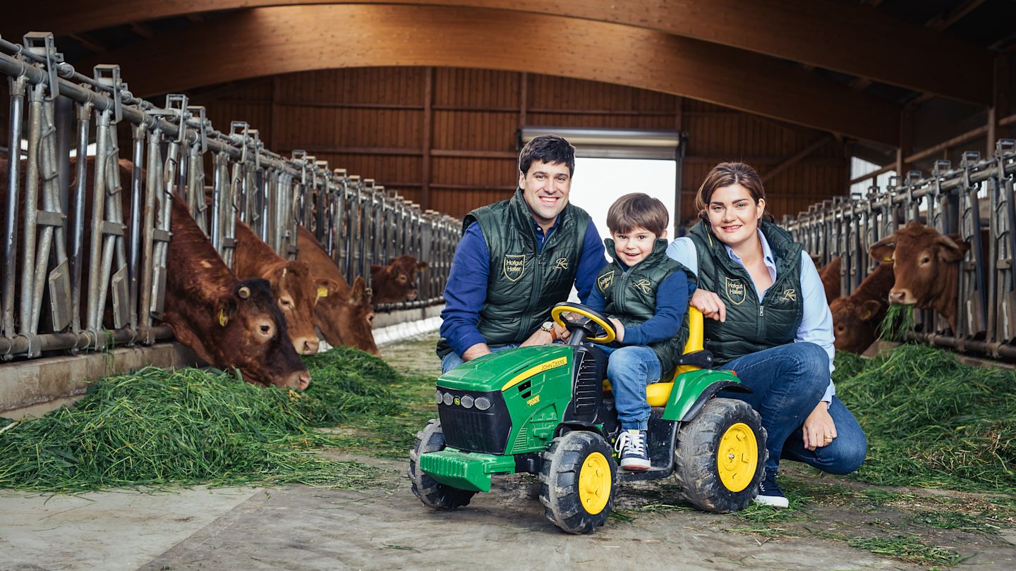 Familie mit Kind posieren in einem Kuhstall für die Kamera.