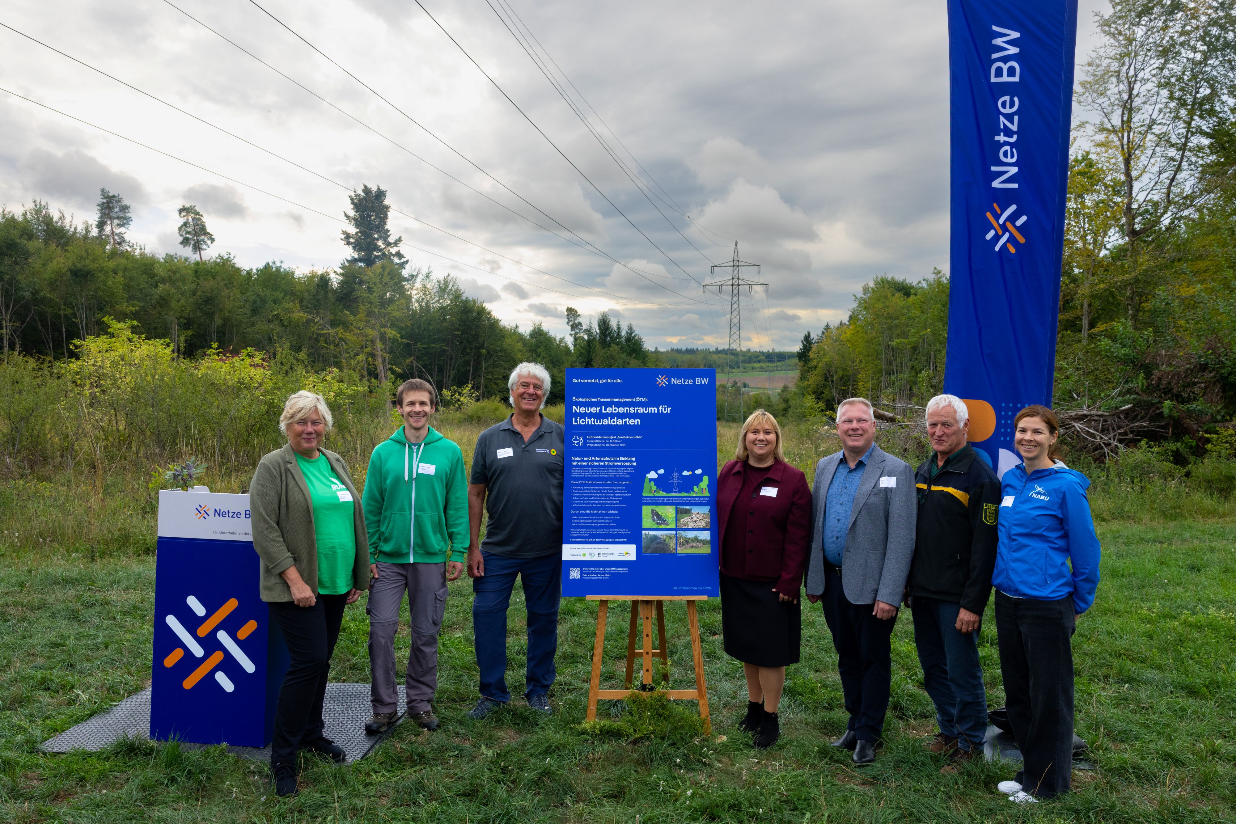Gemeinsam mit Vertreterinnen und Vertretern aus Kommunen, Naturschutz und Forstwirtschaft enthüllte Selma Lossau, Geschäftsführerin Region Mitte und Technik der Netze BW, eine Infotafel zum Ökologischen Trassenmanagement. Sie informiert Wanderer und Ausflügler über das Lichtwaldartenprojekt in der Nähe der Sontheimer Höhle. Das Bild zeigt (von links): Sylvia Pilarsky -Grosch Landesvorsitzende BUND Landesverband Baden -Württemberg e.V. ), Dr. Heiko Hinneberg (RP Tübingen, Referat 56, Referent für Artenschutz ), Hans Offenwanger (Biosphärengebiet Schwäbische Alb, Naturschutz und Ranger -Koordination ), Dr. Selma Lossau (Geschäftsführerin Region Mitte und Technik der Netze BW), Michael Weber (Gemeinde Heroldstatt, Bürgermeister ), Michael Thorwarth (ForstBW, Betriebsleitung Vorstandsvertretung ) und Pia Schmidt (NABU Landesverband Baden -Württemberg e.V., Projektmitarbeiterin Dialogforum Energiewende und Naturschutz ). © Netze BW GmbH