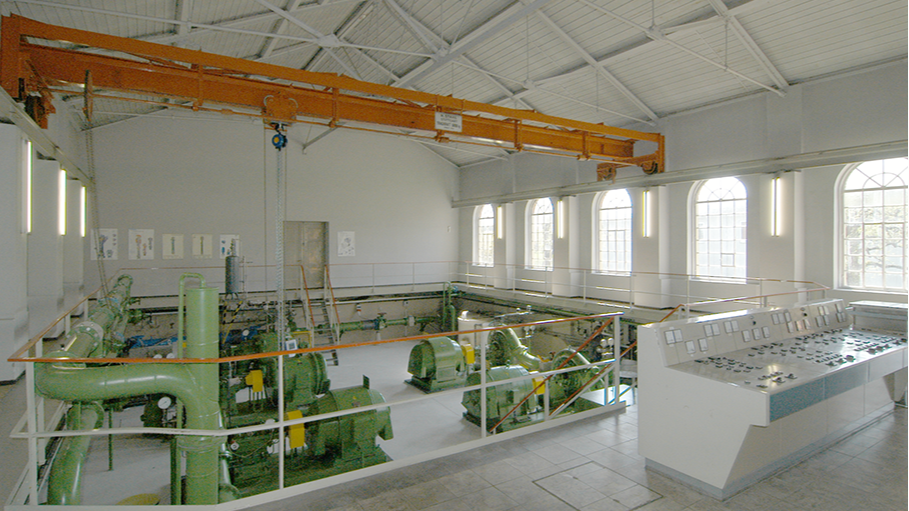 Pumpwerk-Innenansicht mit Kran und Steuerpult.