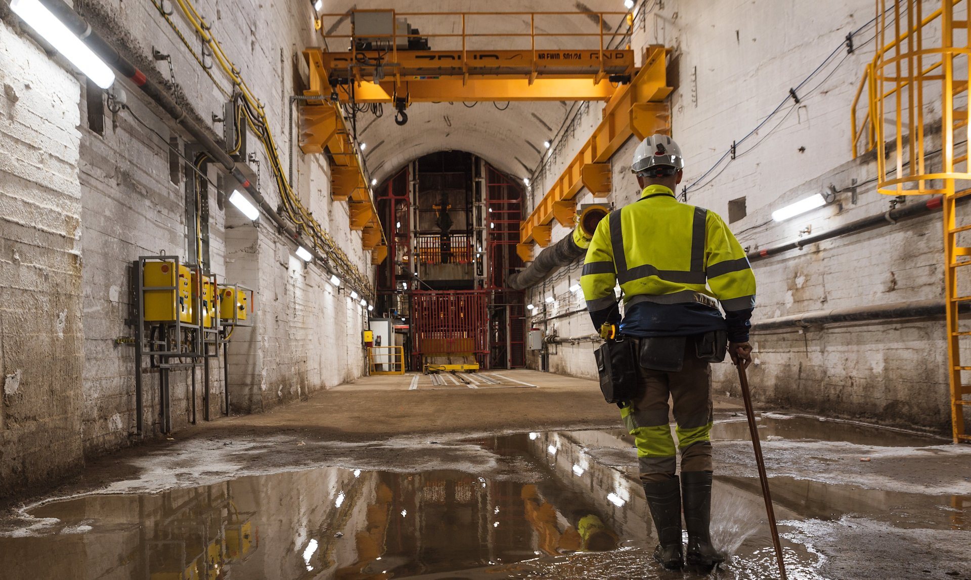 Arbeiter mit Helm in unterirdischer Anlage.