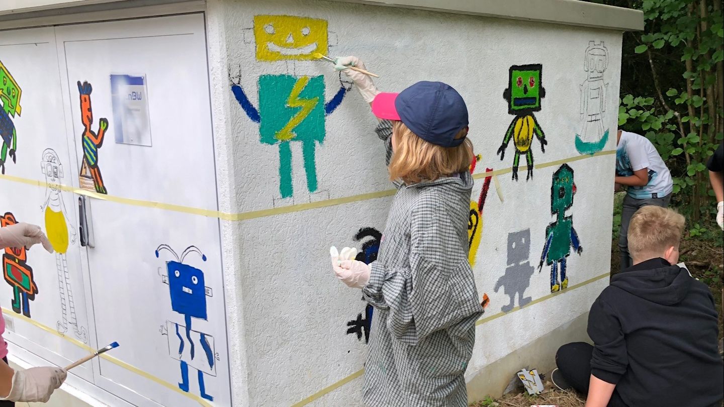 Kinder malen Roboter auf einen Verteilerkasten.