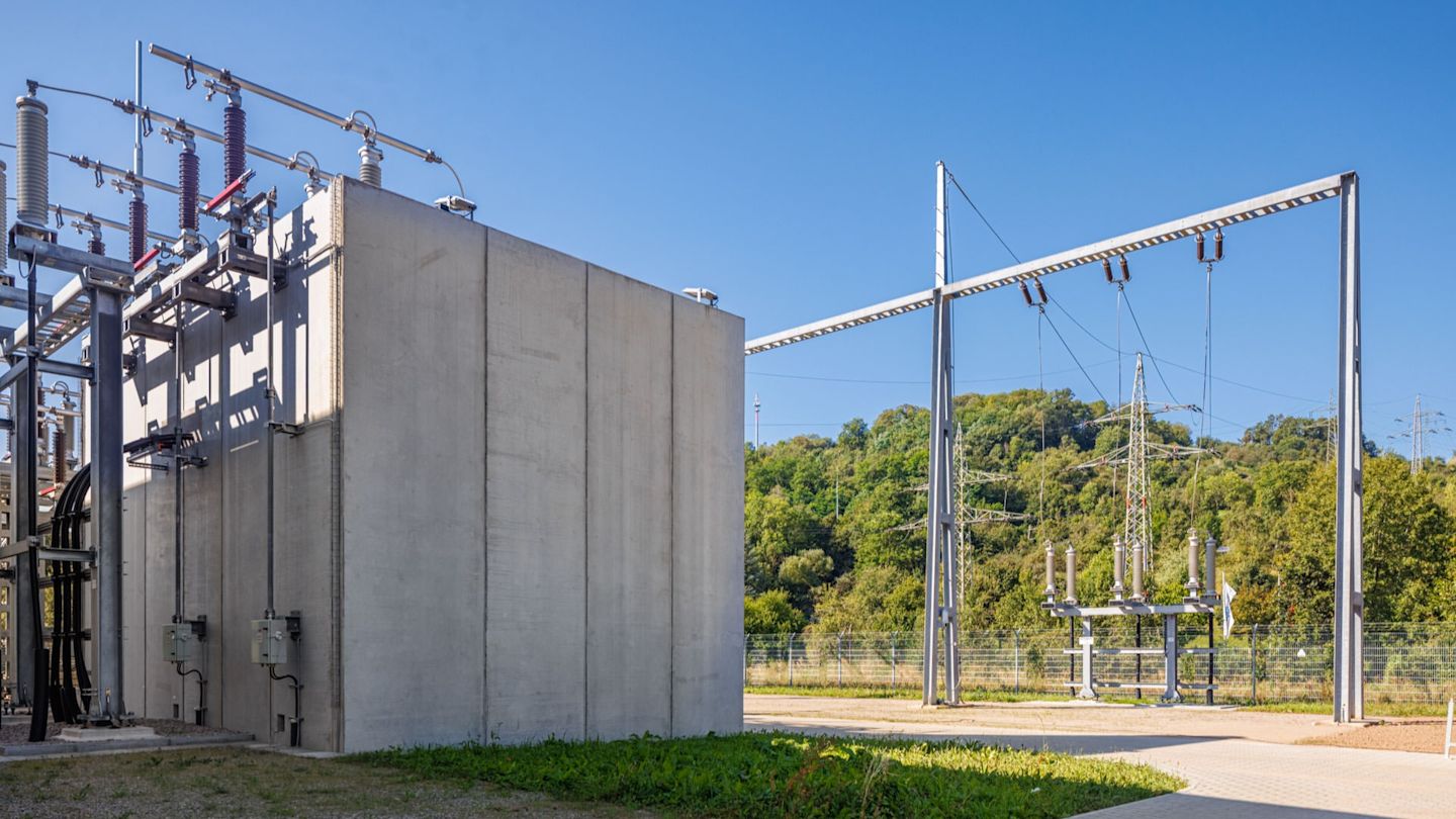 Umspannwerk mit Betonwand und Freileitung.