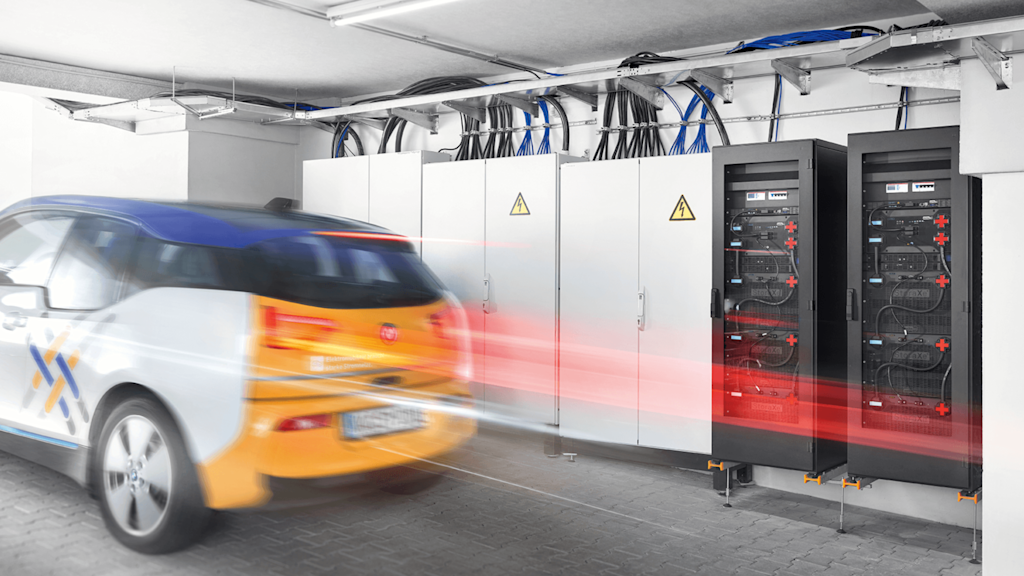 E-Auto fährt an in Tiefgarage an Technikschränken vorbei.