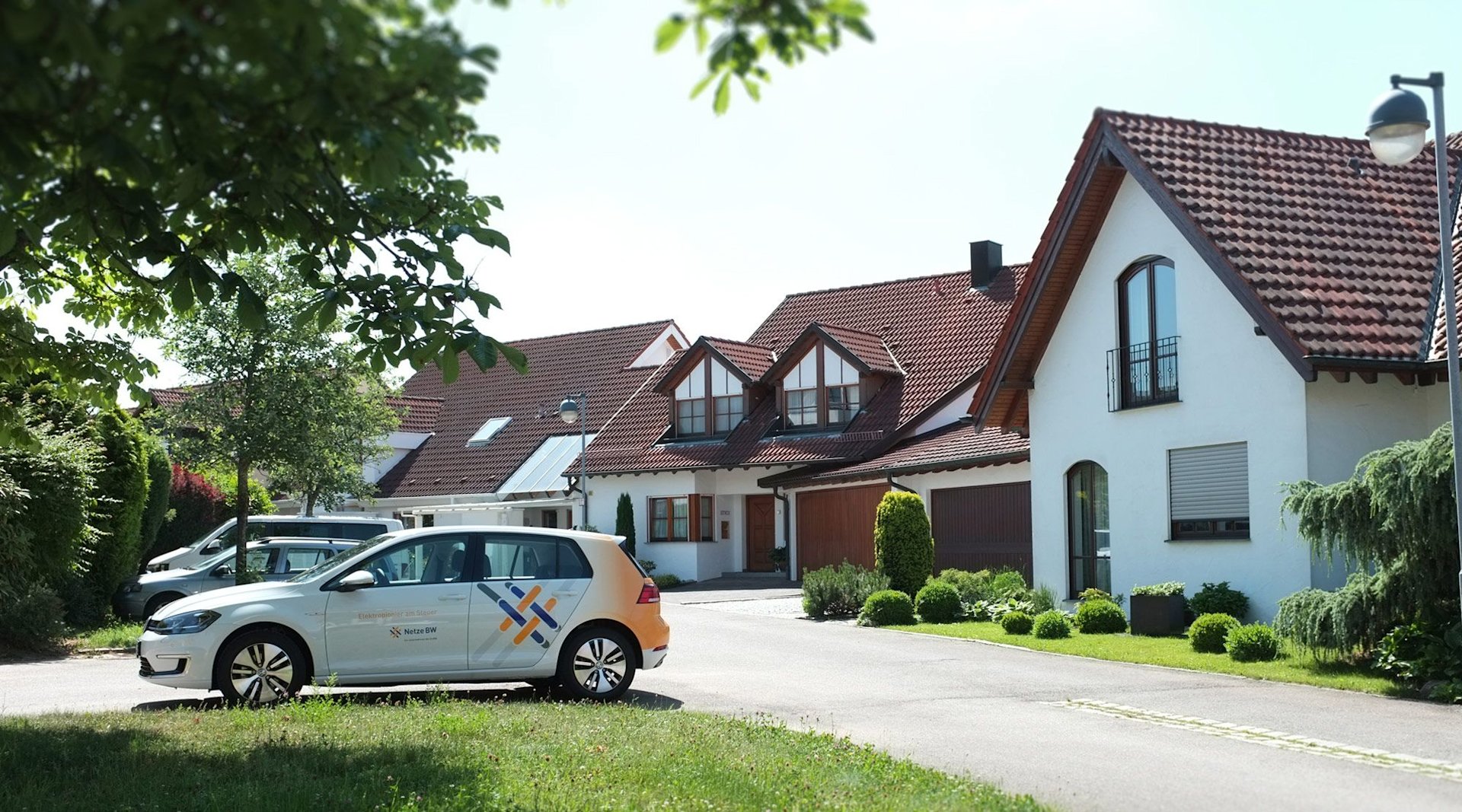 Auto mit Netze-BW-Logo vor Häusern.