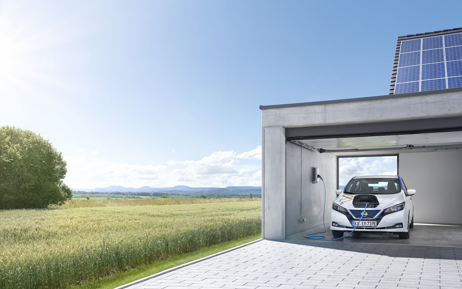 E-Auto lädt in Garage mit Solaranlage, daneben Feld.