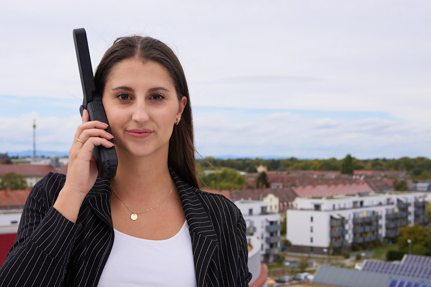 Junge Frau hält Satellitentelefon an ihr rechtes Ohr.