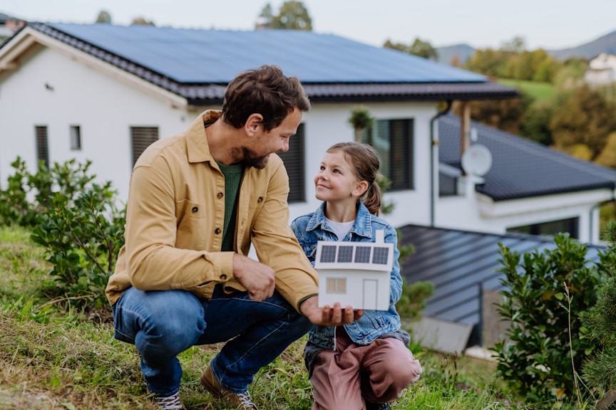 Vater und Tochter mit Hausmodell mit Solarzellen.