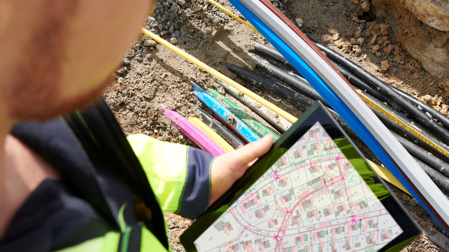 Techniker überprüft Kabelverlegung mit Plan auf Tablet.
