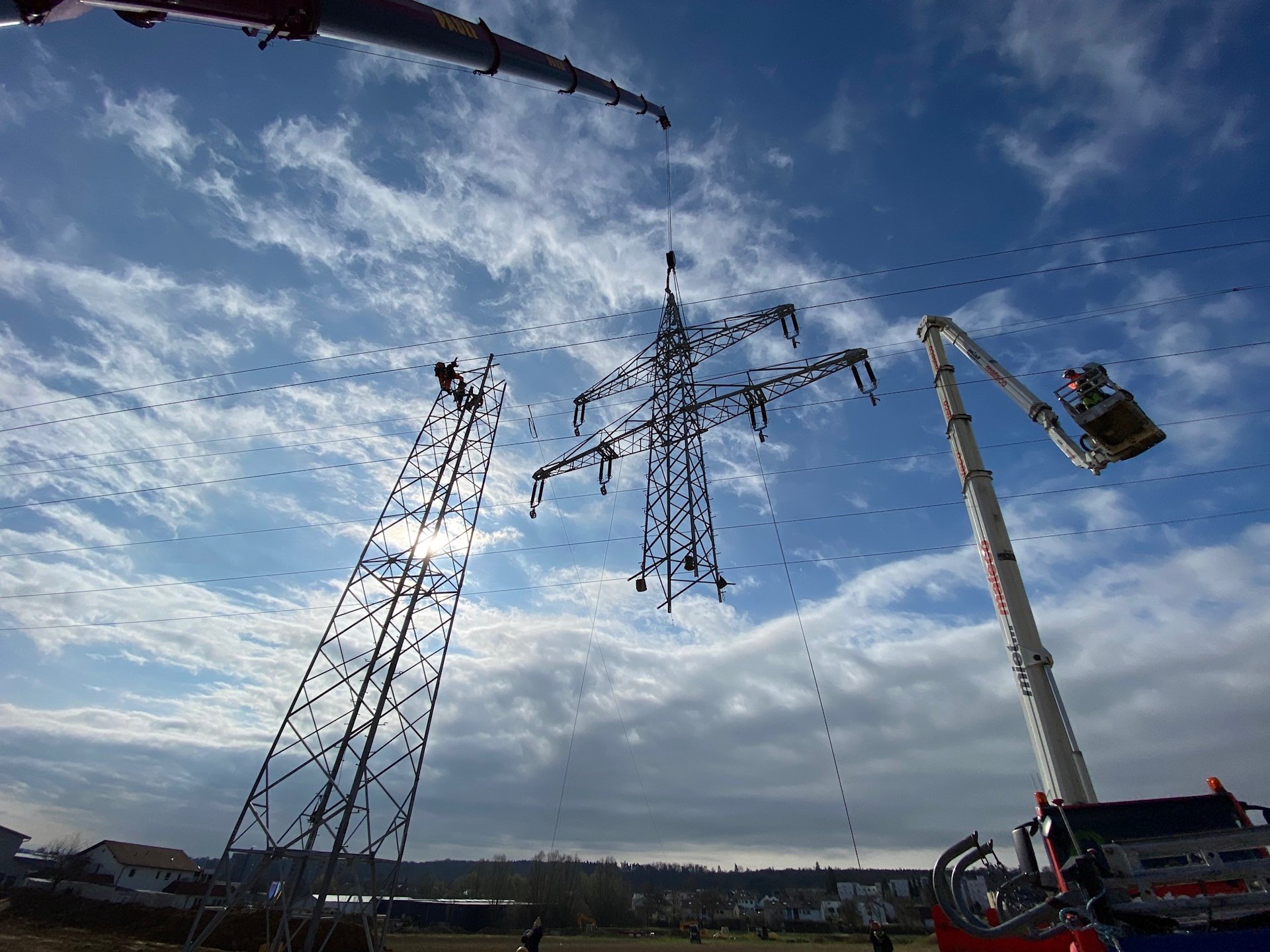 Montage eines Strommastes mit Kran und Hebebühne.