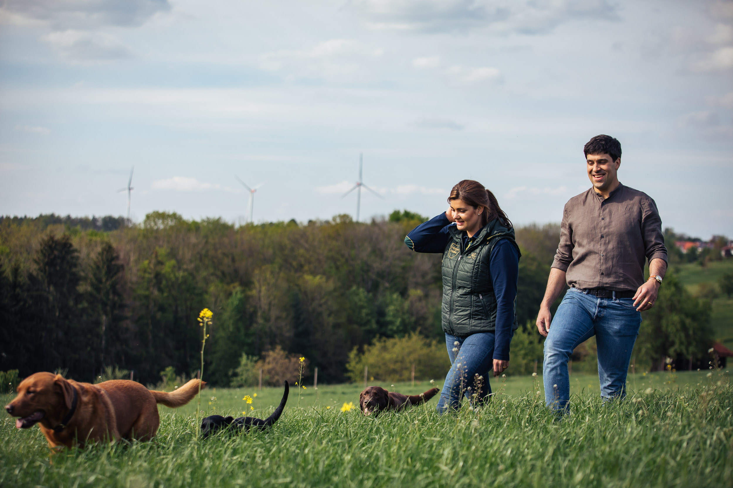 Mann und Frau mit Hunden auf Wiese.