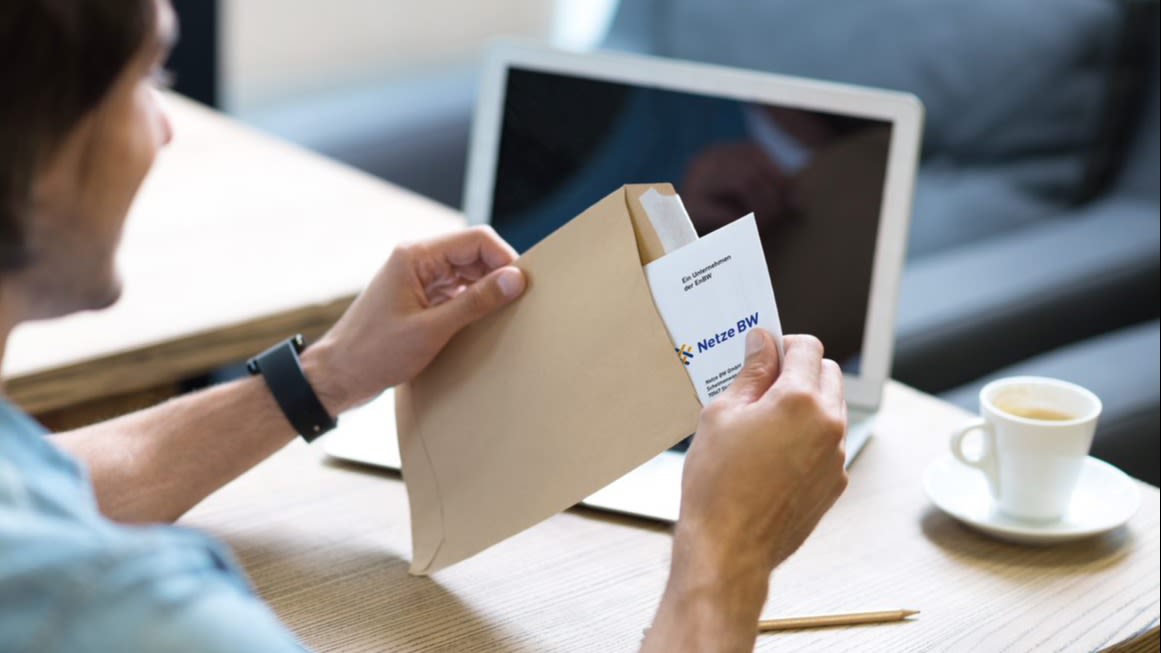 Person öffnet Briefumschlag mit Netze BW Schriftstück.