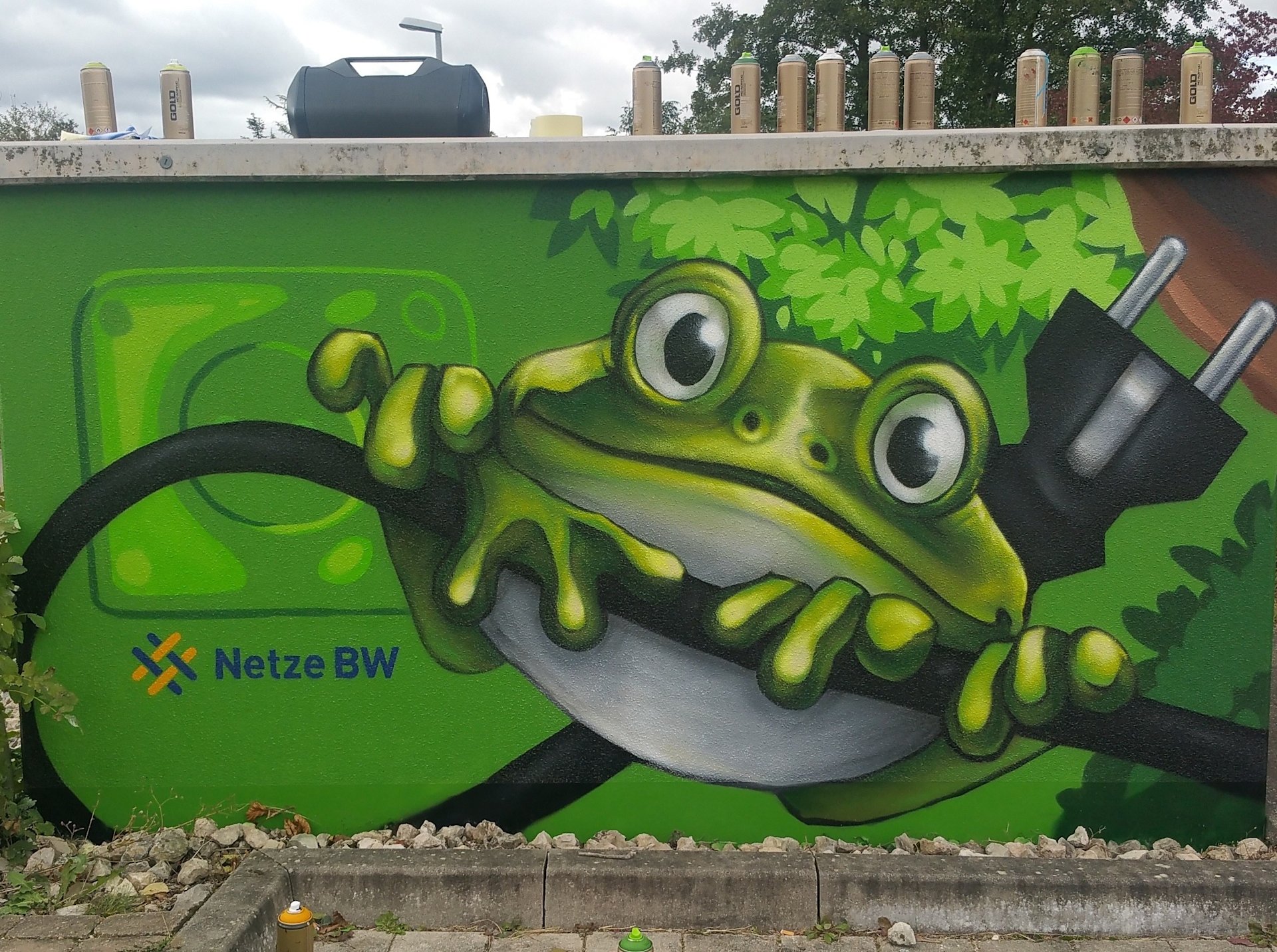 Graffiti auf Trafostation: Frosch an Stromkabel mit Netze-BW-Logo.