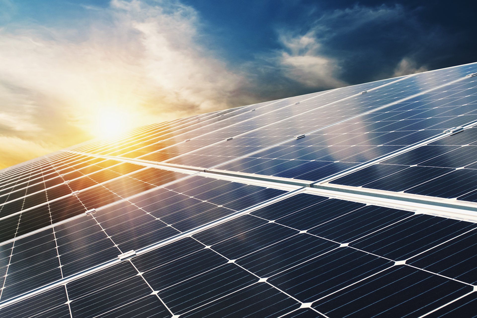 Nahaufnahme von Solarpaneelen mit tiefstehender Sonne am Himmel.