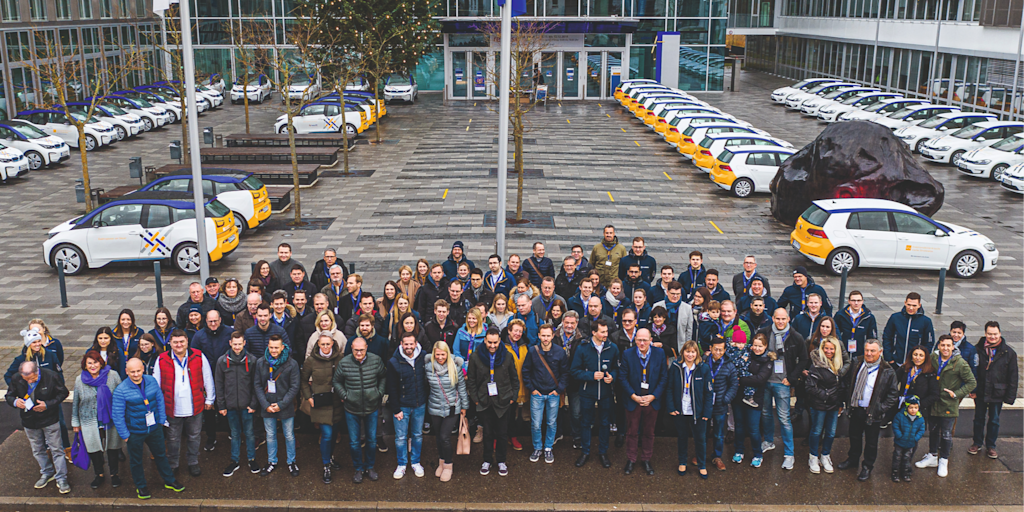 Große Gruppe Menschen vor Elektroautos mit Netze-BW-Logo.