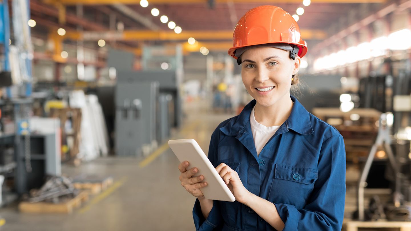 Technikerin in Fabrik mit Tablet in der Hand.