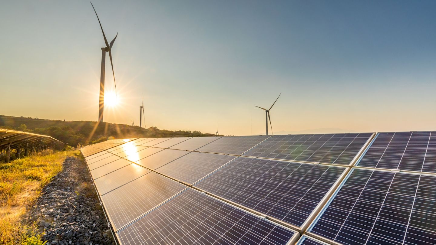 PV-Anlage im Sonnenschein im Hintergrund Windräder.