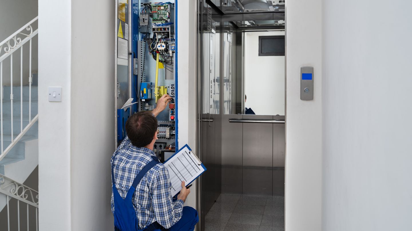 Ein Mann setzt einen PegelMeter bei der Aufzugsmontage ein.