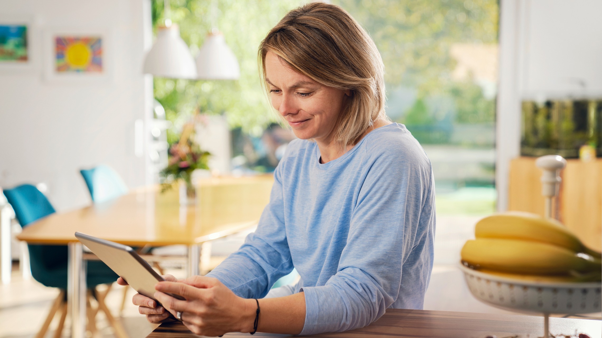 Frau benutzt Tablet am Küchentisch.