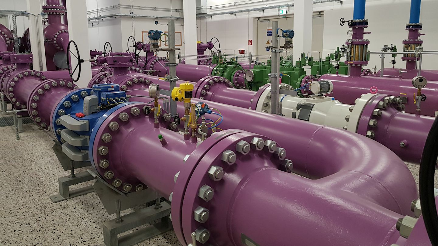 Lilafarbene Rohrleitungen in einer Industrieanlage.