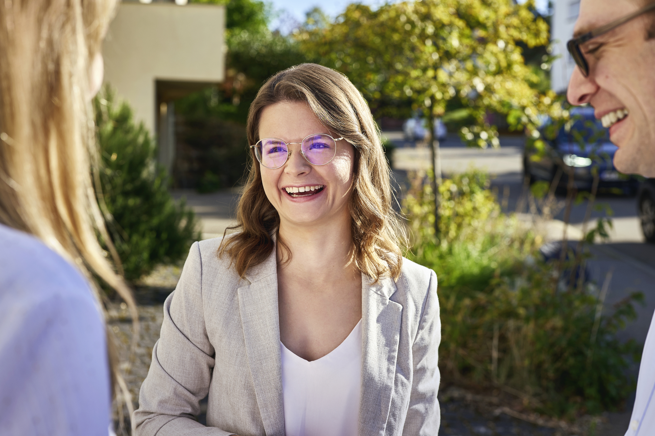 Lächelnde junge Frau mit Brille und im beigen Blazer.