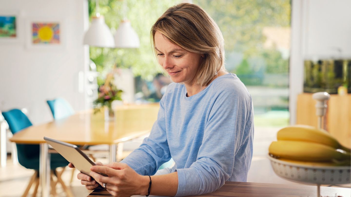 Frau benutzt Tablet im hellen Wohnzimmer.