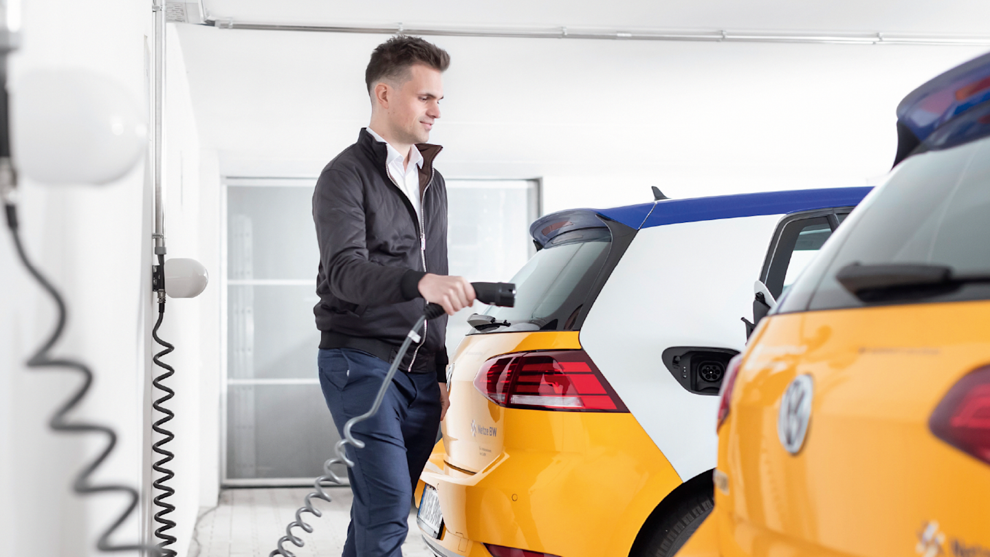 Mann lädt gelbes Elektroauto.