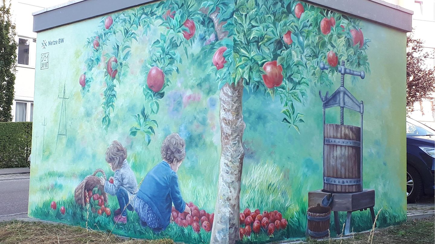 Graffiti: Kinder pflücken Äpfel unter Apfelbaum, daneben eine Apfelsaftpresse.
