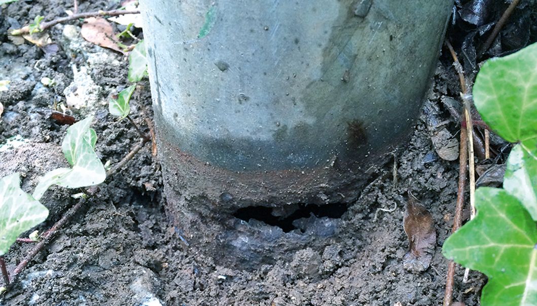 Rost am Metallpfosten im Erdreich.