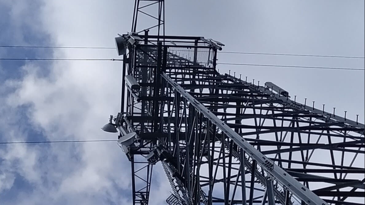 Sendemast mit Antennen vor Wolkenhimmel.