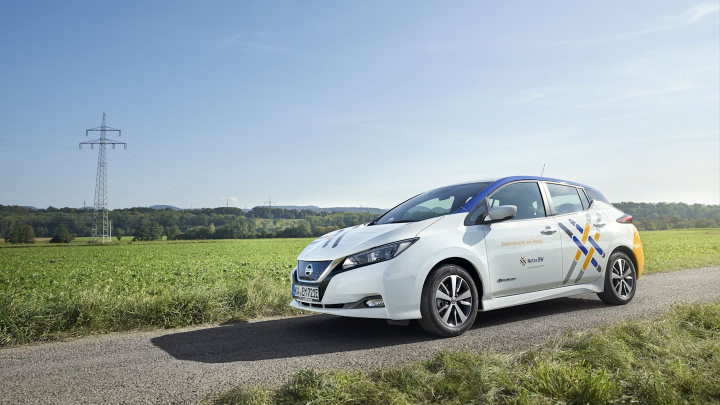 Weißer Nissan mit Netze-BW-Aufschrift steht auf Feldweg.