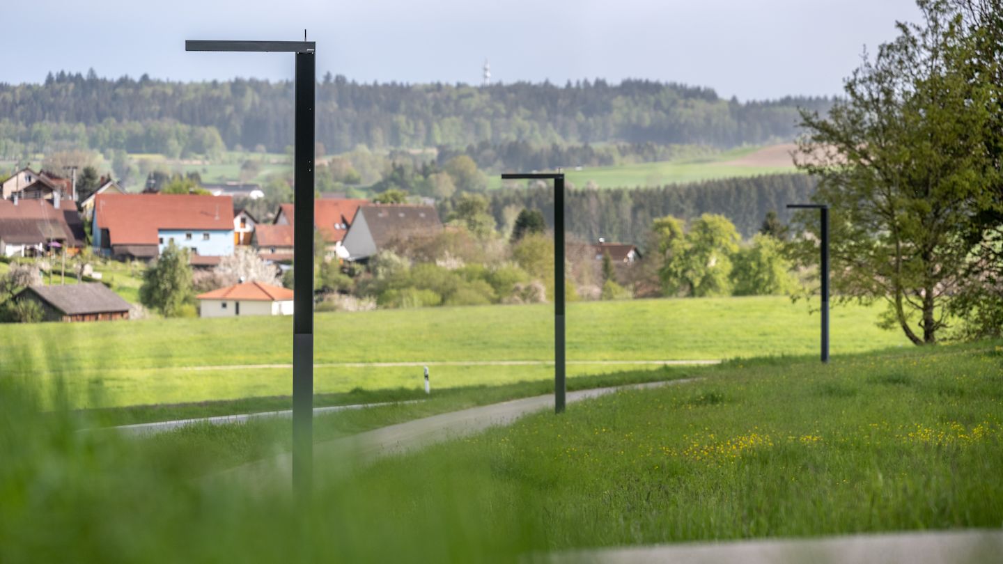 Grüne Landschaft mit einem Weg und smarten Straßenlaternen.