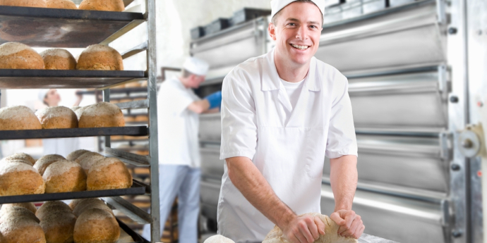 Lächelnder Bäcker knetet Teig.