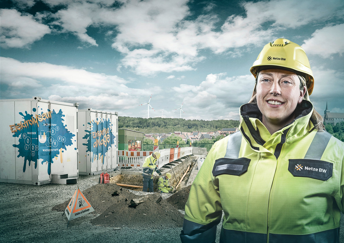 Netze-BW-Mitarbeiterin mit Helm vor Elektrolyseanlage.