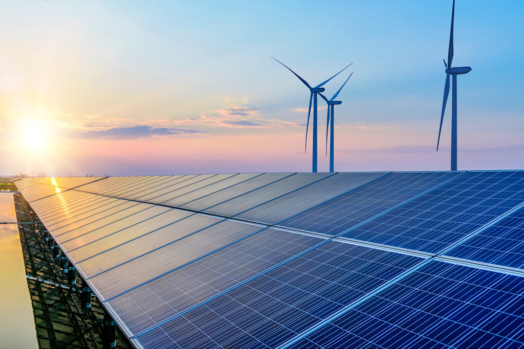 Sonnenuntergang über Solaranlage und Windkraftanlagen.