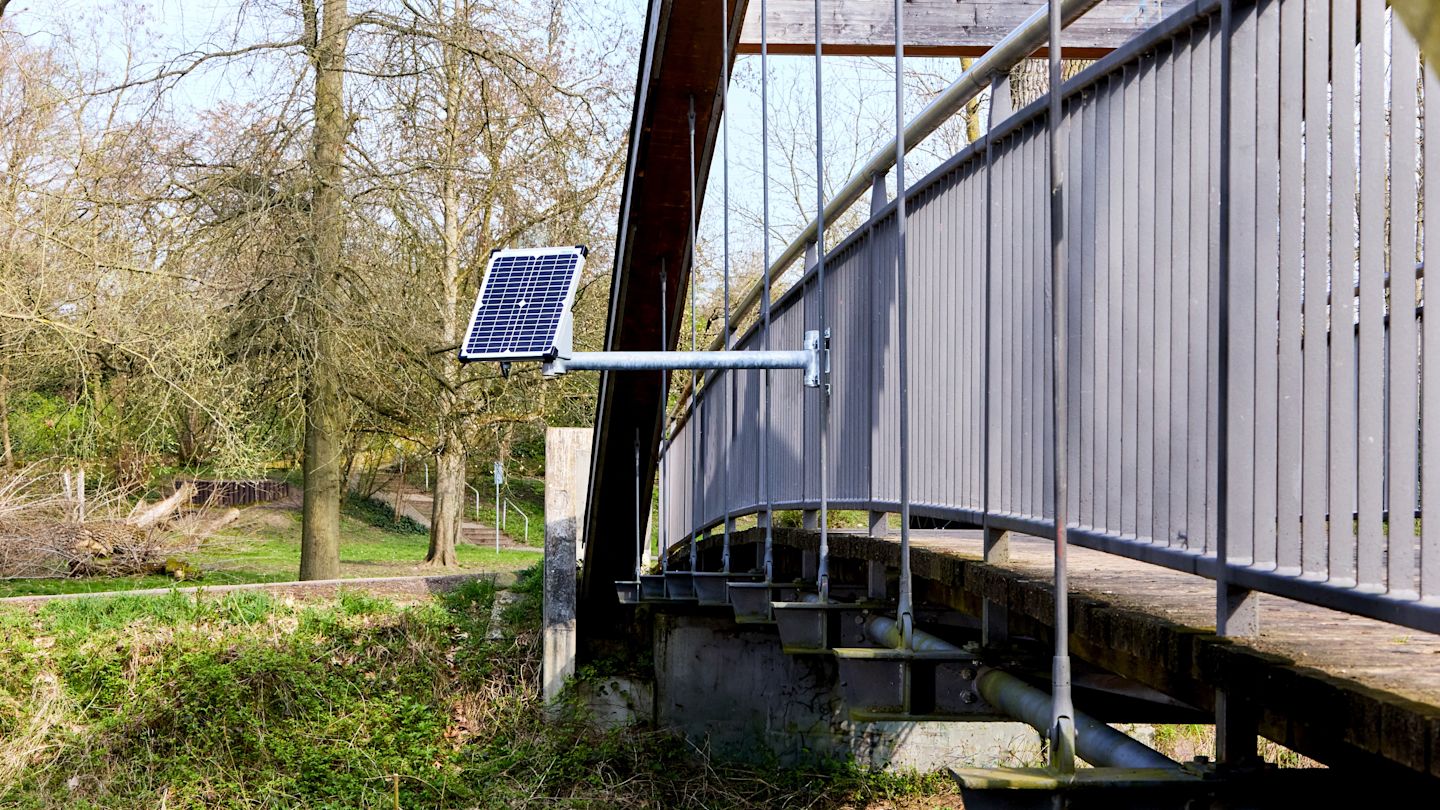 An einer Brücke ist ein Hochwassersensor befestigt.
