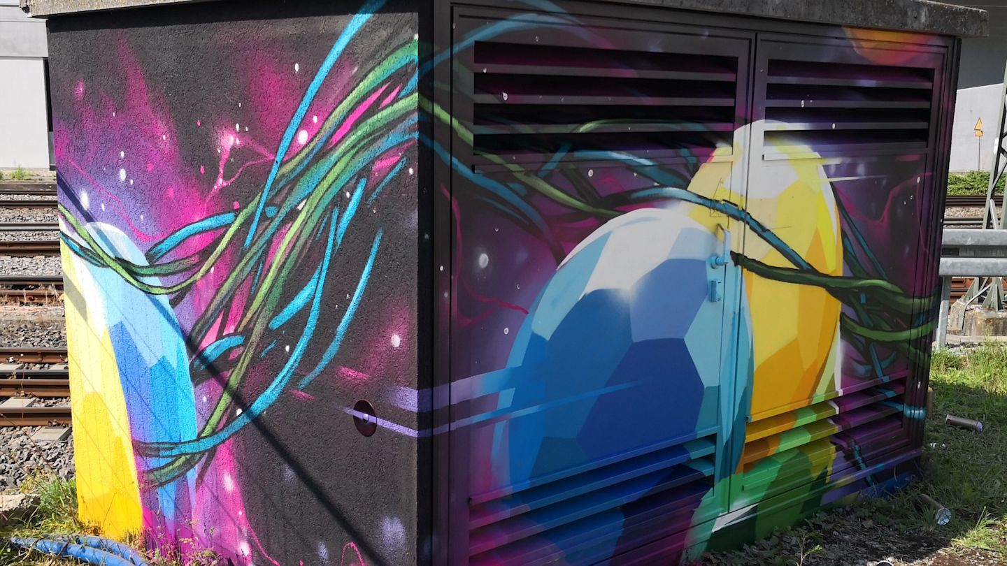 Graffiti-Kunst an einem Schaltkasten: farbige Kugeln und Ranken.