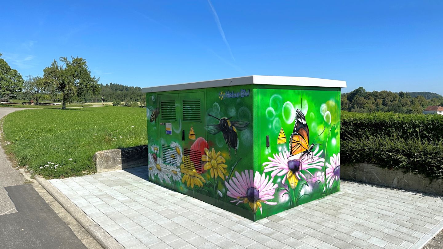 Grüner Stromverteiler mit Blumen- und Insektenmotiv.