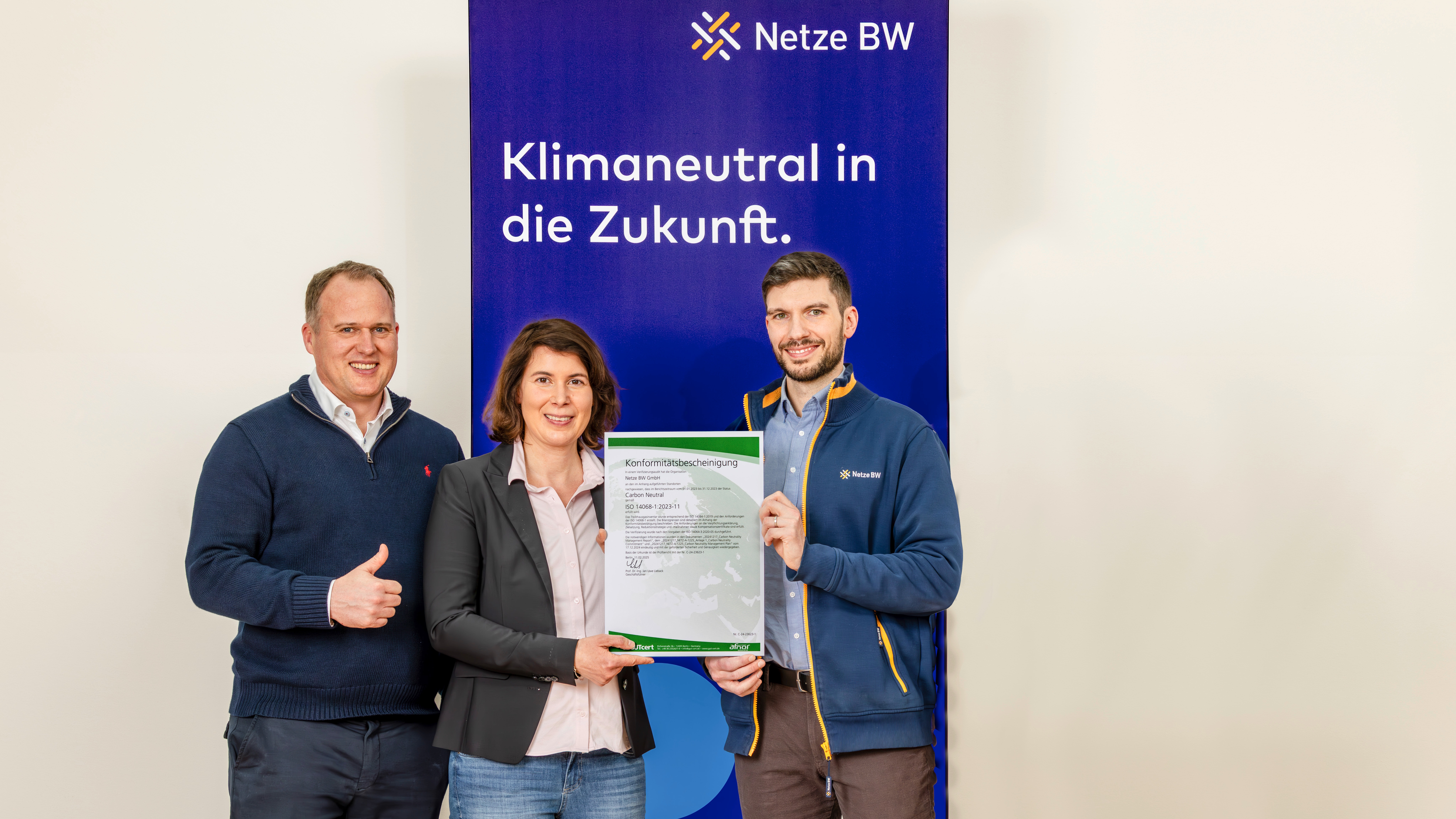 Drei Mitarbeitende mit Urkunde zur Klimaneutralität.
