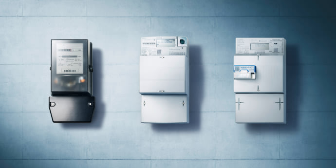 Drei elektronische Stromzähler an einer Wand.