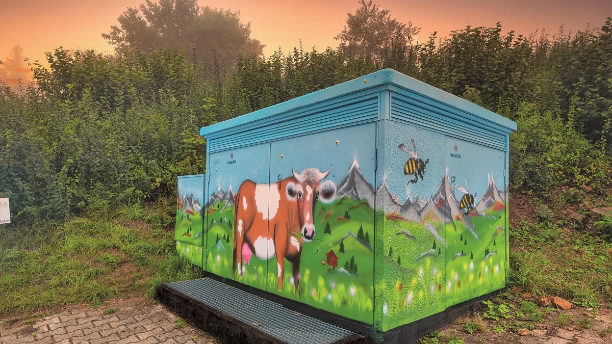Graffiti: Blauer Stromkasten mit Kuh- und Bienenmotiv.