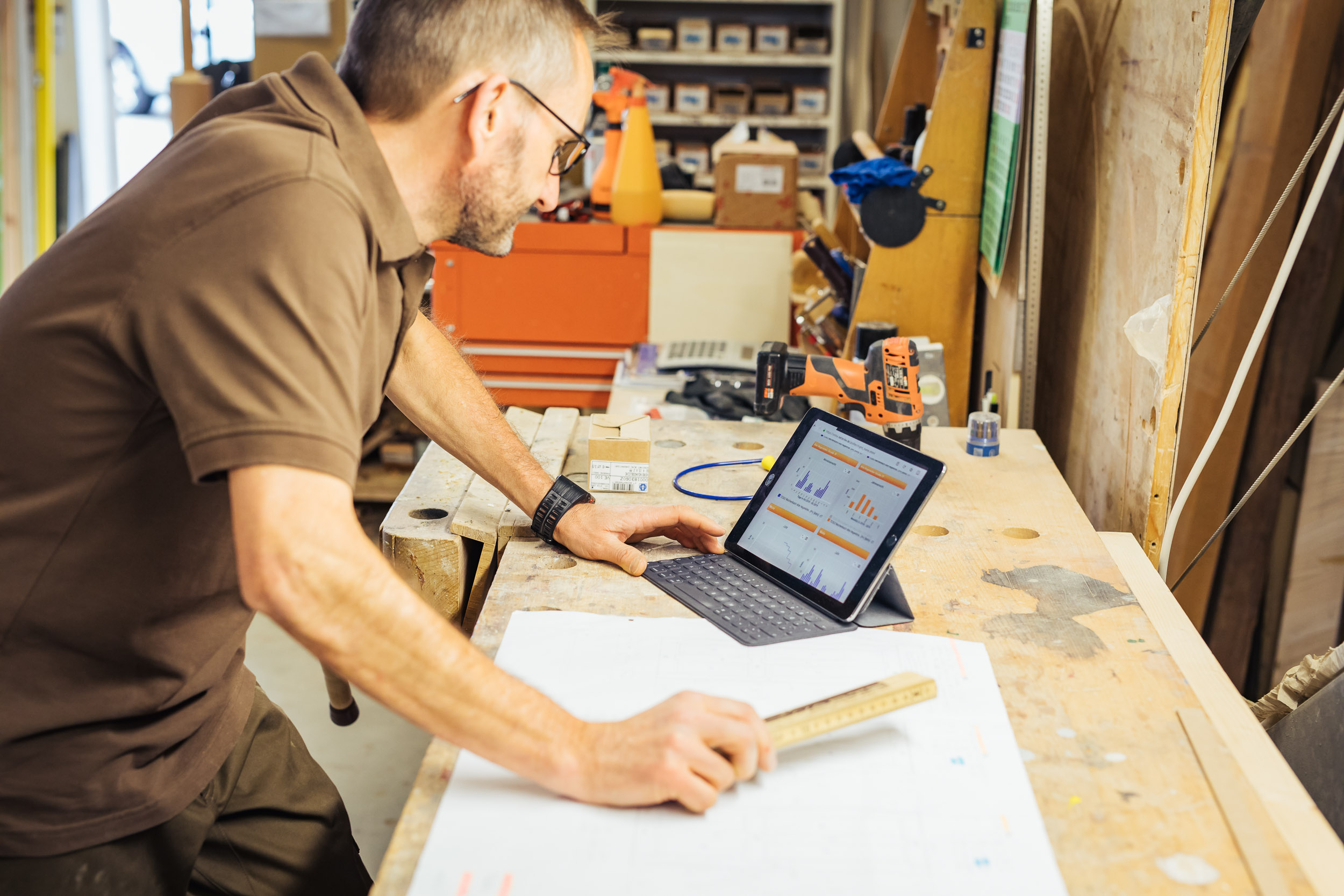 Handwerker überprüft Daten auf Tablet in Werkstatt.