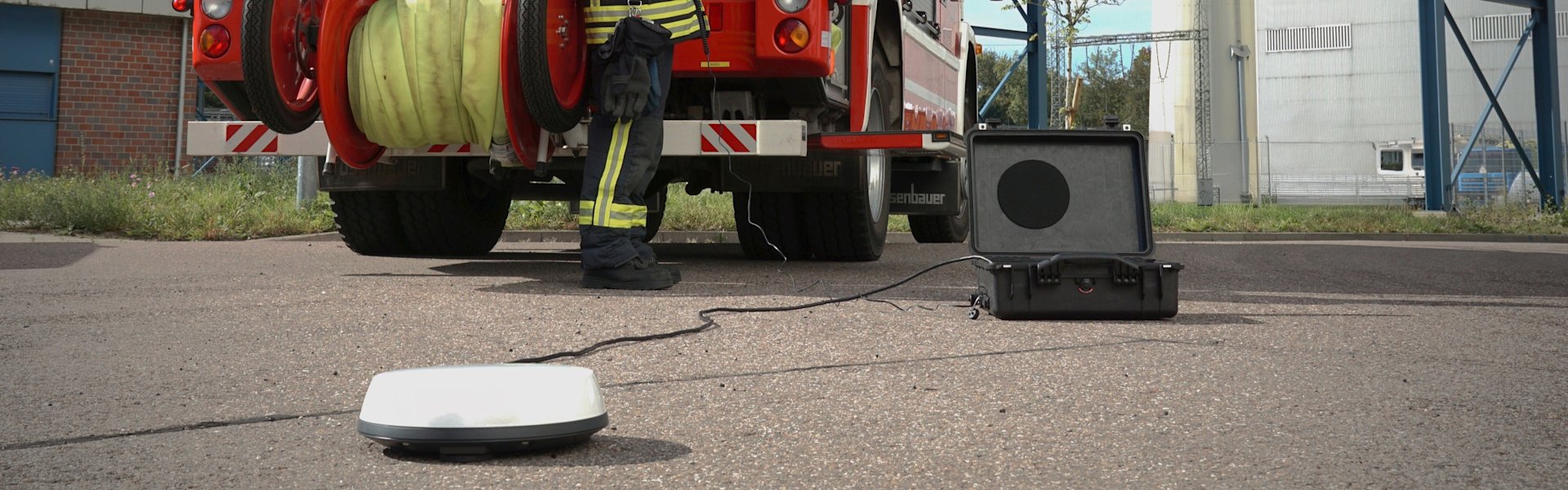 Geöffneter Transportkoffer für Satellitenkommunikation vor Löschfahrzeug.