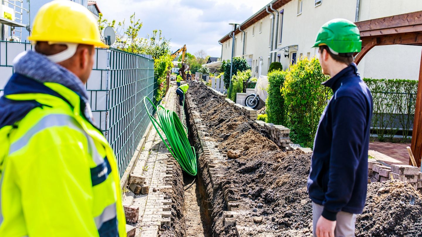 Bauarbeiter verlegen Kabel in einem Graben.