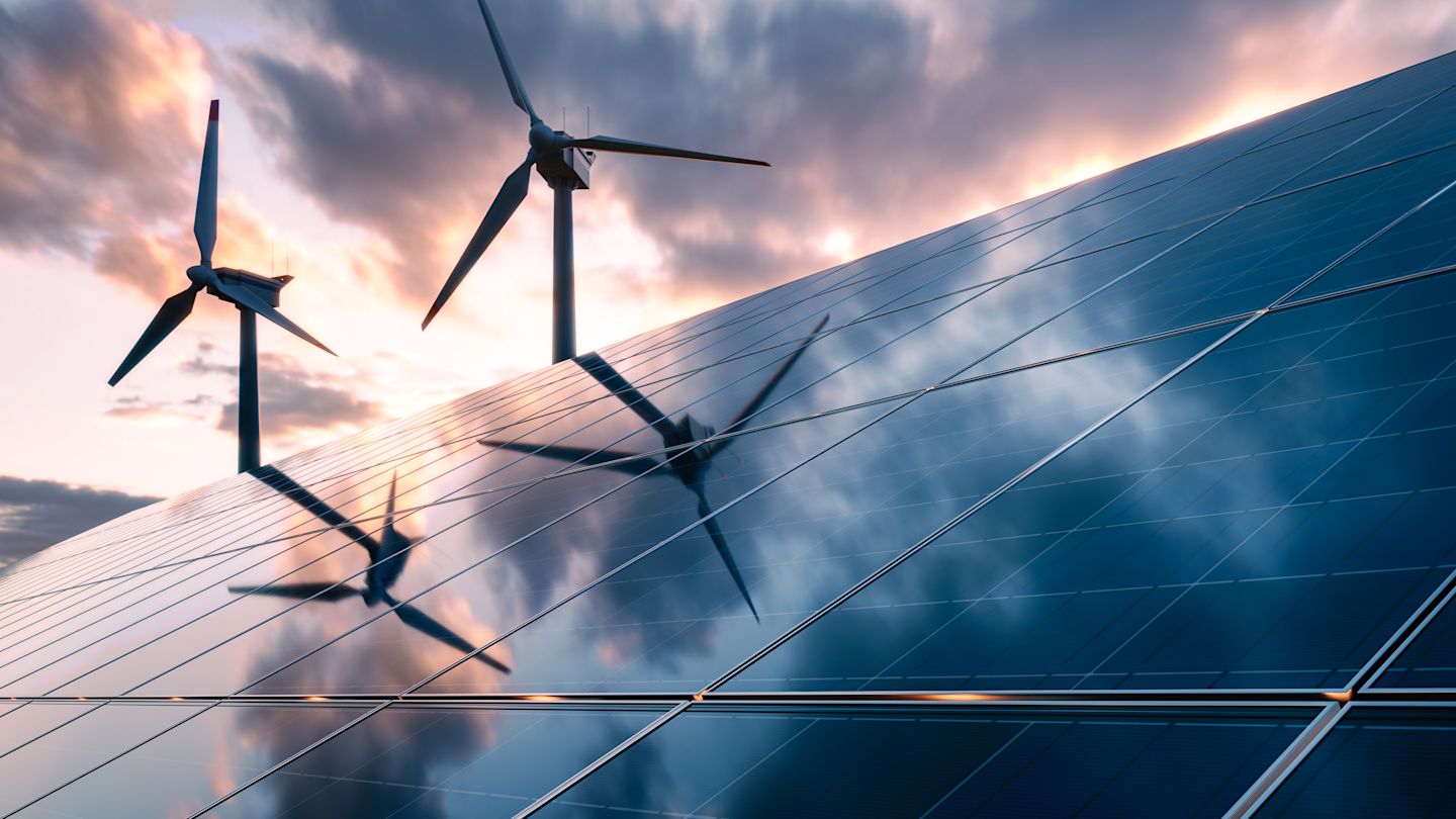 Windräder und Solarpanels bei Sonnenuntergang.