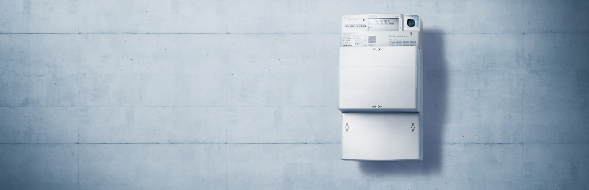 Weißer Stromzähler an Betonwand.