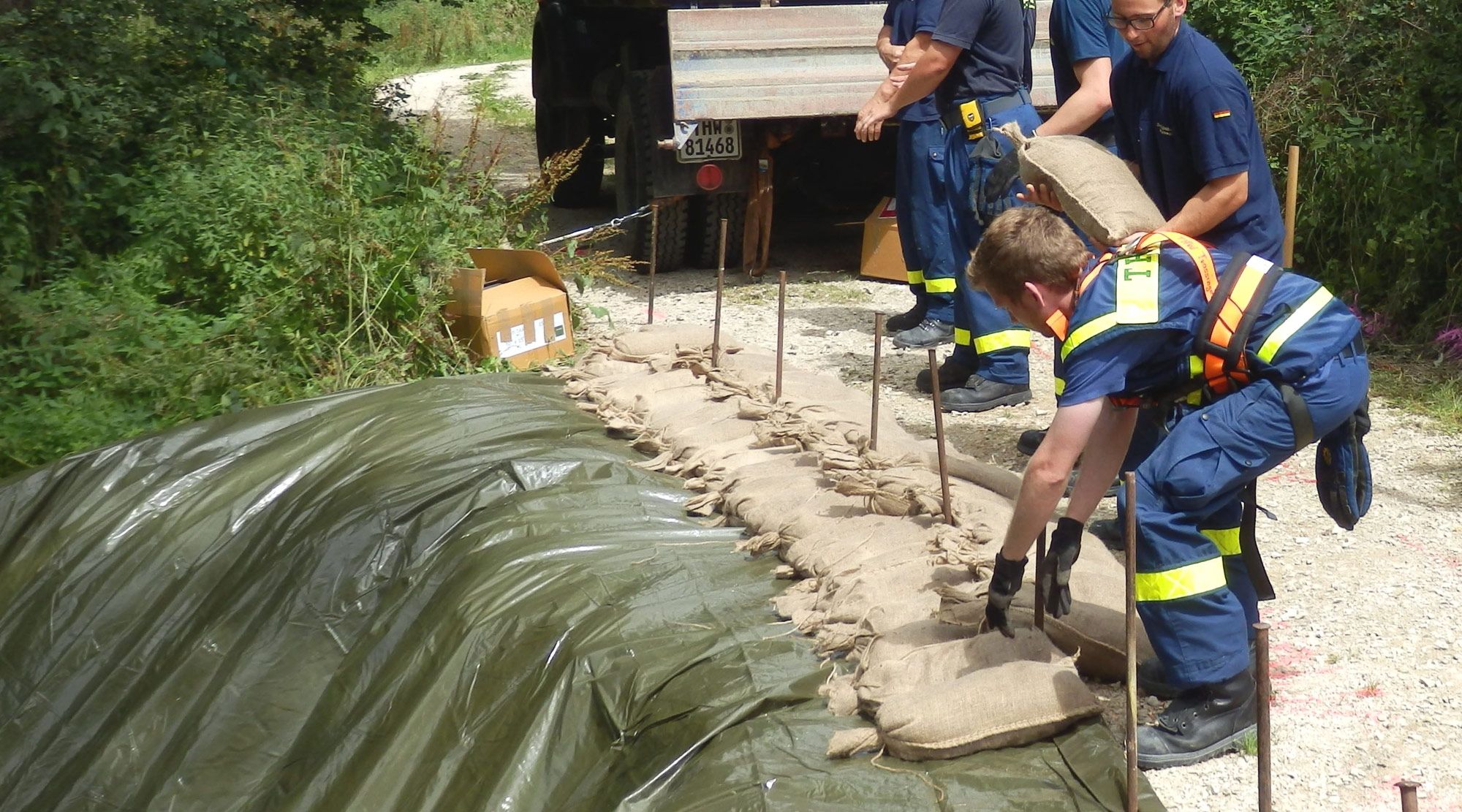Männer vom THW legen Sandsäcke auf eine Folie.