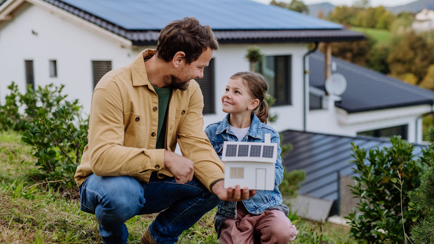 Mann und Mädchen mit Solardach-Modell in der Hand.